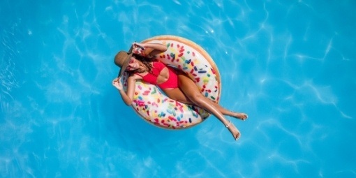 woman in red bikini and sun hat floating in pool on donut floaty